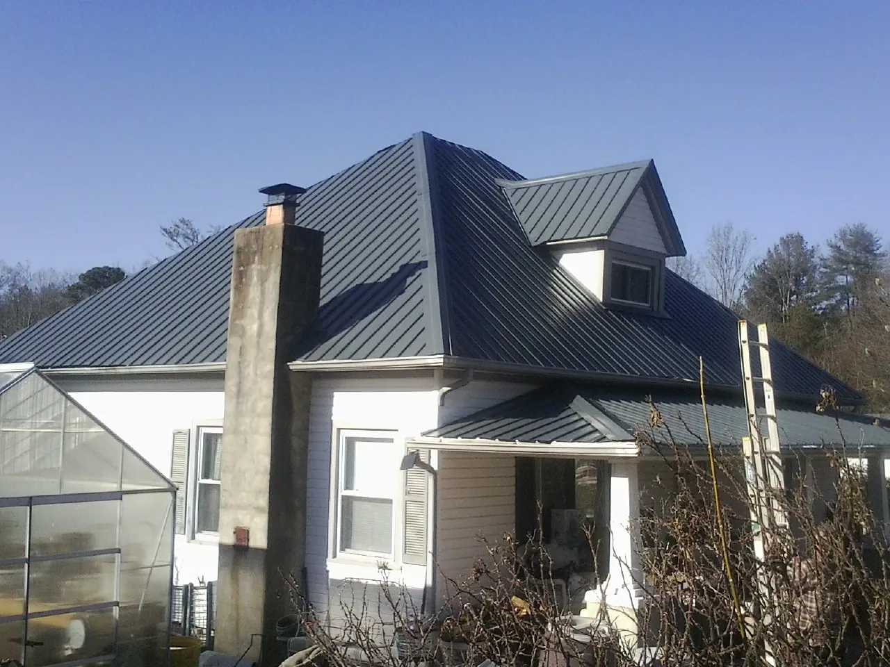 Dark blue standing seam metal roof on a white farmhouse with dormer — Slate & Tile Roof Repair by Roofing Brothers in Vernonia