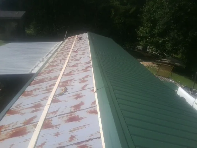 Old rusted panels beside newly installed green metal roofing — Wind Damage Roof Repair by Roofing Brothers in Vernonia