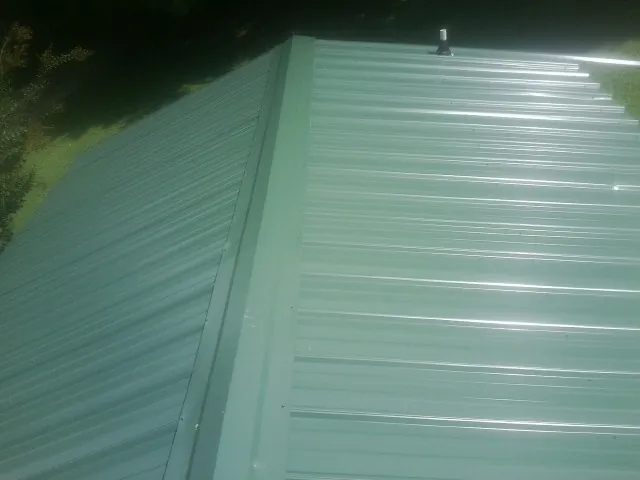 New green metal panels meeting at the ridge of a roof — Flat Roof Repair work by our crew in Vernonia