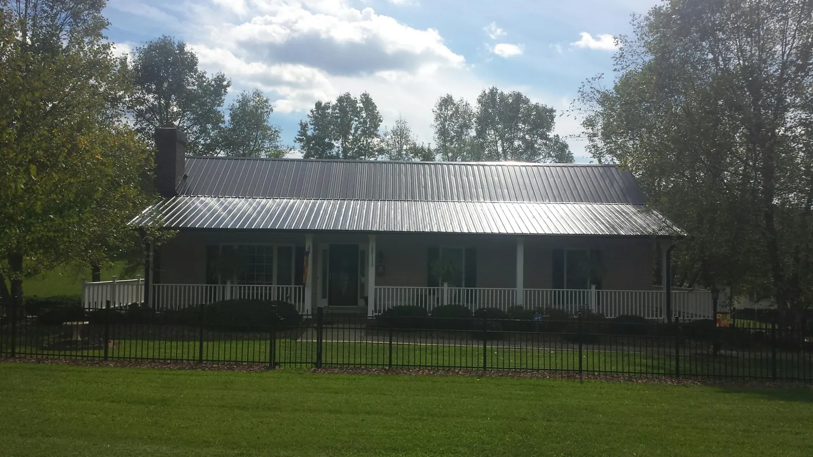 Gray metal roof on a brick ranch with a full width front porch — Gutter Guard Installation work by our crew in Vernonia