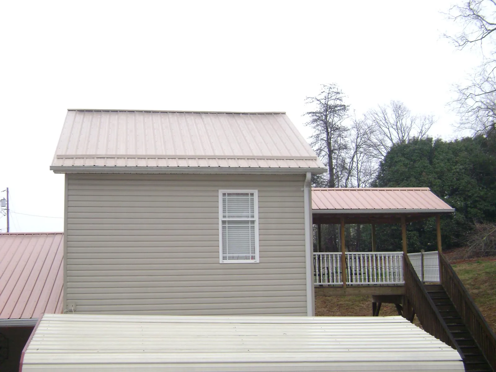 Tan metal roofs on a two story addition and attached porch, from a Roof Replacement job in Vernonia