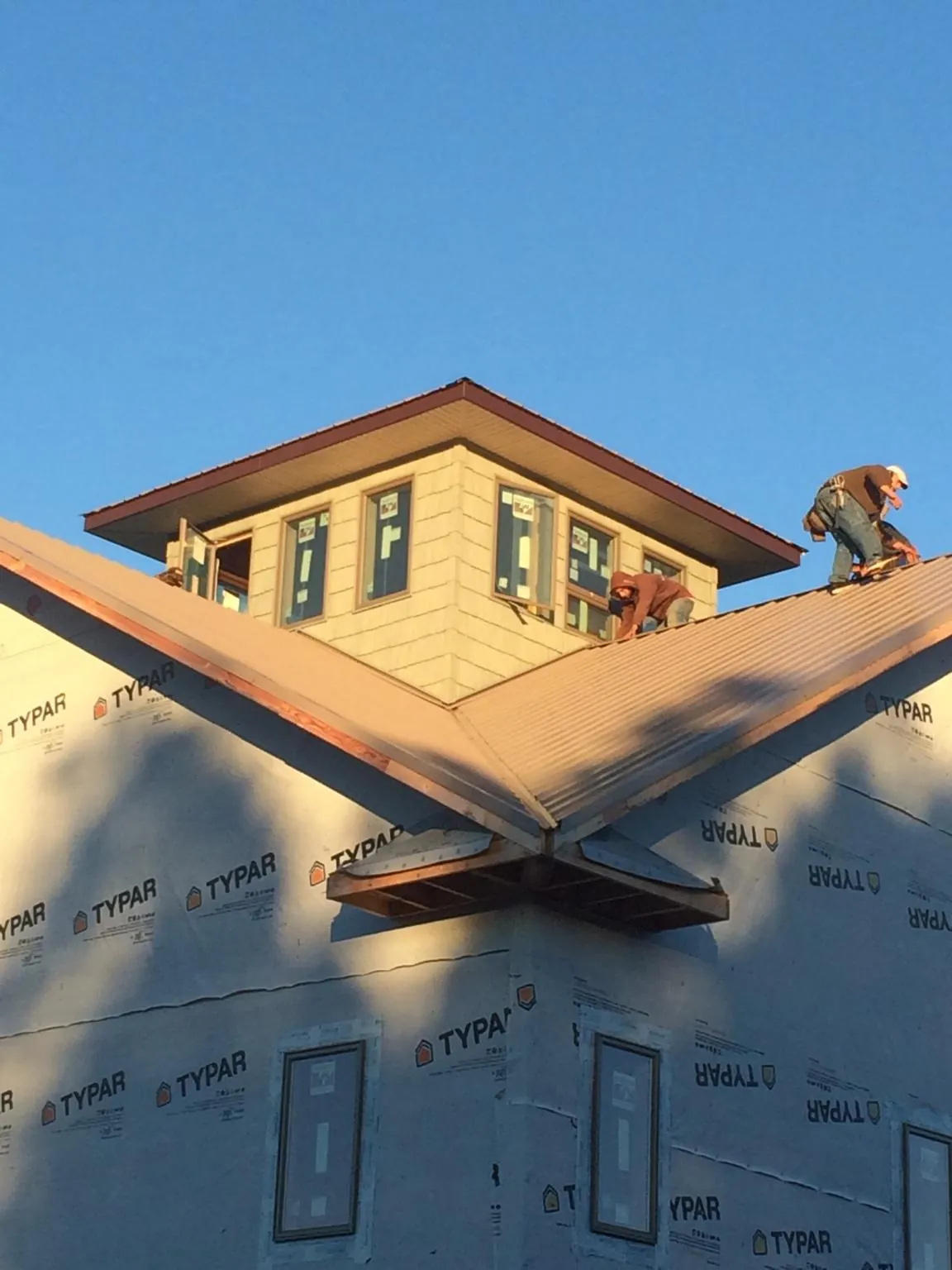 Roofers working around a rooftop cupola on a new metal roof at sunset — Roof Waterproofing in Vernonia by Roofing Brothers